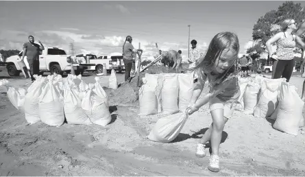  ?? AP-Yonhap ?? Chloe Heeden, 4, drags a sandbag to her father’s car in Virginia Beach, Va., Wednesday as Hurricane Florence moves toward the eastern shore.