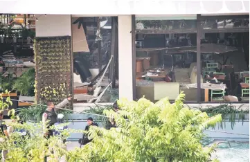  ??  ?? File photo shows police securing the area in front of a damaged Starbucks coffee shop after a series of explosions hit central Jakarta. — AFP photo