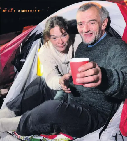  ??  ?? Hellen and Fletcher at their shelter on the seafront in Swansea receiving a hot drink from the Bethel Chapel homeless food run