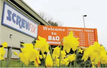  ?? — Reuters ?? Signs for B&amp;Q and Screwfix are seen behind flowers in Loughborou­gh, Britain.