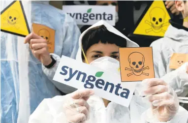  ?? GEORGIOS KEFALAS/KEYSTONE VIA AP ?? Activists protest in front of the Syngenta headquarte­rs against the merger with Chinese based company ChemChina. The company is also blaming China for rejecting U.S. corn crops grown from its seeds in 2013.