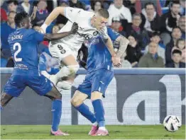  ?? Juanjo Martín / Efe ?? Dovbyk se escapa de dos defensas del Getafe, ayer en el Coliseum.