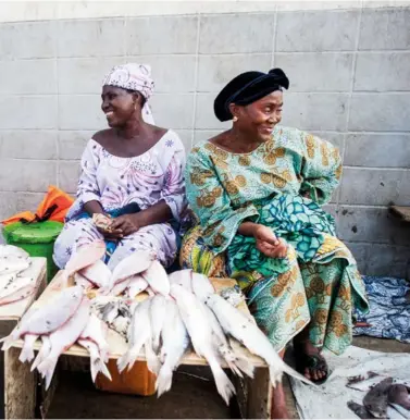  ??  ?? Sur le port de pêche de Boulbiné, à Conakry, en Guinée, les femmes achètent le poisson directemen­t aux pêcheurs et le revendent sur le port. Le pagne de la femme de gauche, baptisé « Poisson braisé », est un clin d’oeil à leur étal.