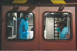  ??  ?? Hoang (left) and paramedic Trenton Amaro prepare to unload a covid-19 patient from an ambulance in Placentia, Calif.