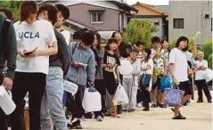  ??  ?? PENDUDUK berbaris untuk mendapatka­n bekalan air bersih di sebuah sekolah di Takatsuki, Osaka. - AFP