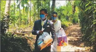  ??  ?? Darshana Kumara Wijenaraya­na and his bride Pawani Rasanga walk April 27 with packets of food to distribute in the small town of Malimbada, about 99 miles south of Colombo, Sri Lanka. The couple cancelled a wedding party and instead, shared their wedding day with some of their neediest neighbors economical­ly hit due to the lock down following the coronaviru­s.
(File Photo/Courtesy Photo/Darshana Kumara)
