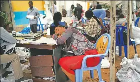  ?? AP/JEROME DELAY ?? A Congolese independen­t electoral commission official rests Sunday as results are tallied for the presidenti­al election at a local results compilatio­n center in Kinshasa, Congo.