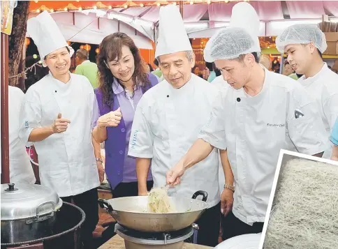  ??  ?? Li Wenbo (holding chopsticks) shows Sibu Hin Hua Clan Associatio­n chairman Soo Teck Kee (on his right) how Hin Hua bee hoon is cooked.