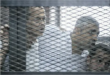  ?? KHALED DESOUKI/AFP/Get ty Images ?? Egyptian-Canadian Mohamed Fahmy, centre, listens Monday to the verdict delivered against him and fellow Al-Jazeera journalist­s Australian Peter Greste, left, and Egyptian Baher Mohamed in a defendants’ cage in Cairo.