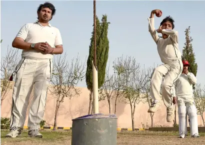  ?? AFP ?? six-year-old eli Mikal Khan delivers a ball as his father abdullah Khan, who is a local cricket coach and runs an academy, watches during a cricket bowling practice in Quetta. —