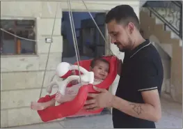  ?? GHAITH ALSAYE — THE ASSOCIATED PRESS ?? Khalil al-Sawadi plays with his adopted daughter Afraa in Jinderis, Syria, on Saturday. Afraa was born under the rubble of her family home, destroyed by the deadly earthquake that hit Turkey and Syria six months ago, killing her parents and siblings.