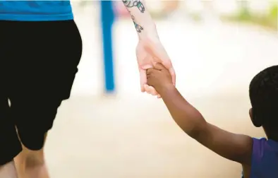  ?? KENDALL WARNER/STAFF ?? Alexis Oakley, an assistant teacher at Children’s Harbor Ghent in Norfolk, holds the hand of one of her students, Jakari Young, while playing outside in June.