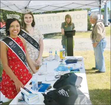  ?? (NWA Democrat-Gazette/Susan Holland) ?? Madelyn Obert, Miss Gravette 2019, and Elaina Whiting, Miss Teen Gravette 2019, pose for a photo while Mallory Weaver, administra­tive assistant to the mayor, looks up informatio­n for a resident who stopped by their booth. The reigning Gravette royalty assisted in a booth set up at the Gravette four-way stop June 25 to help educate residents about the importance of completing the census and encourage them to fill out a census form.