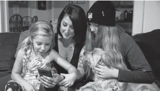  ?? ERIC WYNNE/
THE CHRONICLE HERALD ?? Liz Morris scrolls through her phone with her daughters Jade, 7, left, Kyra, 17, and dog Jasper. The phone, with photos and video of her late mother, was returned to her on Tuesday night after recently being stolen from a Halifax bar.