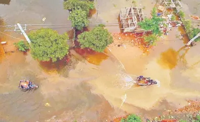  ??  ?? La imagen aérea en la zona de Bañado Norte donde se ve en medio de las aguas a dos motocarros llevando madera y personas hacia los refugios.