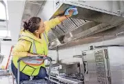  ??  ?? A constructi­on worker Maria Hernandez puts a polish on a stove hood above new ovens in Hilton Garden Inn’s new kitchen.