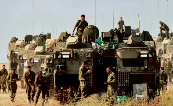  ?? MENAHEM KAHANA/AFP VIA GETTY IMAGES ?? Israeli soldiers stood near armored personnel carriers at a position near the border with Gaza in Israel on Wednesday.