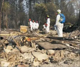  ?? SUDHIN THANAWALA — THE ASSOCIATED PRESS FILE ?? Volunteer members of an El Dorado County search and rescue team search the ruins of a home, looking for human remains, in Paradise following a wildfire.