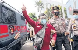  ??  ?? An activist is led away by police Saturday as a rally against the coup in Myanmar is dispersed near the Associatio­n of Southeast Asian Nations in Jakarta, Indonesia.