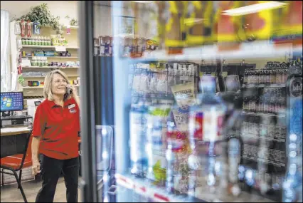  ??  ?? Store clerk Michele Schaffer answers the phone at Village Market and Mercantile in Blue Diamond. “I just fell in love with this place,” said Schaffer, who moved from Washington in 2006. “But the world is changing.”