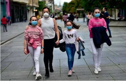  ?? AP ?? A family goes for a walk at Carlos III promenade, in Pamplona, after the Spanish government lifted rules that kept children inside during the coronaviru­s outbreak.