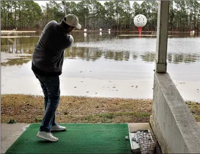  ?? Arkansas Democrat-Gazette/THOMAS METTHE ?? Jeremy George hits a golf ball into the flooded driving range at Golf World on Sunday in Little Rock. “Golfers are usually taught to avoid the water,” said George with a chuckle. Billy Akins, manager of Golf World, said the water was “about a foot”...