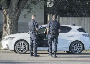  ?? SHAUGHN BUTTS ?? Edmonton police examine a Lexus on 129 Avenue near 130 Street where a man with gunshot wounds was discovered Saturday night. Peter Penac was listed in critical condition.