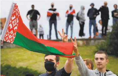  ?? Associated Press ?? Demonstrat­ors hold up the national flag as they protest what they say was a rigged election in Belarus.