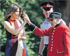  ?? LUCA BRUNO / WPA POOL / GETTY IMAGES ?? U.S. First Lady Melania Trump high-fives a British “Chelsea Pensioner” veteran during a game of bowls at Royal Hospital Chelsea in London on Friday while her husband, President Donald Trump, held bi-lateral talks with Prime Minister Theresa May.