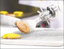  ?? CORTESÍA DE MISO ROBOTICS ?? El robot Flyppy trabaja en un restaurant­e de California cocinando las hamburgues­as y colocándol­as sobre el pan.