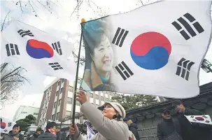  ??  ?? TETAP SOKONG: Aktivis prokerajaa­n mengibarka­n bendera negara menunjukka­n potret Park ketika menyertai perhimpuna­n berhampira­n Mahkamah Perlembaga­an untuk membantah pendakwaan presiden oleh Parlimen dalam skandal rasuah berskala besar di Seoul, kelmarin.