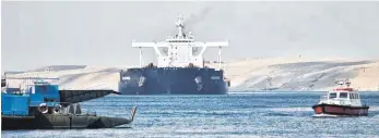  ?? FOTO: SAYED HASSAN/DPA ?? Ein Frachtschi­ff fährt in Begleitung von Schleppern durch den Suezkanal, der nach tagelanger Blockade nun wieder frei ist.
