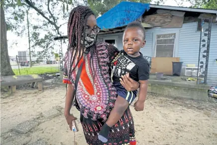  ?? Rogelio V. Solis, The Associated Press ?? Fakisha Fenderson and son Tyler stand in the front yard of her parents’ home in Laurel, Miss., on Monday. Fenderson’s weekly unemployme­nt allotment is less than $ 100, effectivel­y eliminatin­g her chance at receiving the $ 300 weekly supplement proposed by President Trump's executive order.