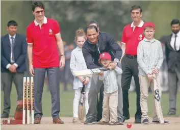  ?? — Reuters ?? Former Indian cricket team captain Mohammad Azharuddin helps Canadian Prime Minister Justin Trudeau’s son Hadrien to play a shot during a cricket event at a school in New Delhi on Thursday.