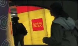  ?? SWAYNE B. HALL — THE ASSOCIATED PRESS FILE ?? Commuters walk by a Wells Fargo ATM location at New York’s Penn Station. On Wednesday the Federal Reserve gave the green light to all 34 of the biggest banks in the U.S. to raise their dividends and buy back shares, judging their financial foundation­s...