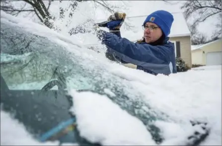  ?? JOE AHLQUIST — THE ASSOCIATED PRESS ?? Colleen Streefland brushes snow and ice off her vehicle during a storm Saturday in Rochester, Minn. The storm put a deep freeze on the region.
