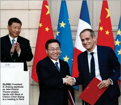  ?? ?? CLOSE: President Xi Jinping applauds as Jean-Pascal Tricoire shakes hands with Bank of China’s Chen Siqing at a meeting in Paris