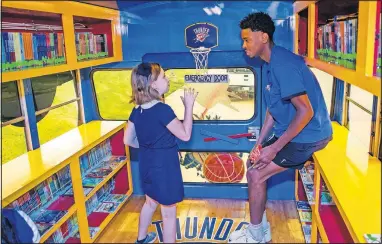  ?? [CHRIS LANDSBERGE­R/ THE OKLAHOMAN] ?? Thunder guard Shai Gilgeous-Alexander talks with third grader Annabelle Thomas as he helps her pick out books Thursday on the Rolling Thunder Book Bus at Eugene Field Elementary.