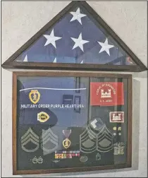  ??  ?? A shadowbox with the medals and awards, including two Purple Hearts, Chapman earned hangs in his living room.