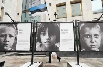  ?? Reuters ?? A person walks past the “Children of Donbass” open-air photo exhibition outside the Estonian Consulate in Moscow on Monday. —