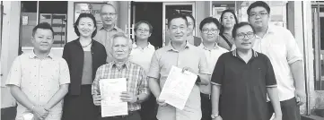  ??  ?? See (front, second right) and Nicholas (front, third right) holding the police report at Simpang Tiga One Stop Centre yesterday.