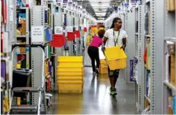  ??  ?? Workers fill yellow totes with merchandis­e on Aug. 2 in the pick mod area of the Amazon Fulfillmen­t Center in Enterprise South Industrial Park.