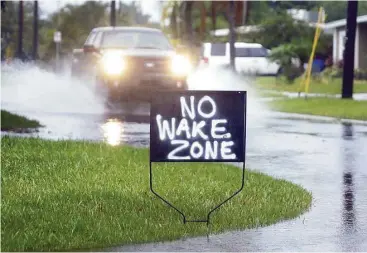  ?? Chris O’Meara / Associated Press ?? A resident of Shore Acres in St. Petersburg, Fla., has a sign urging motorists to slow down on flooded streets on Tuesday. Remnants of Tropical Storm Colin continued to dump rain along Florida’s Gulf Coast.