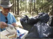  ?? FELICIA FONSECA — THE ASSOCIATED PRESS ?? John Dobson combs through his belongings from a site in the national forest outside Flagstaff, Ariz. Dobson left the campsite because the area is closed to the public, part of multiple closures of national forest land around Arizona due to extreme fire...