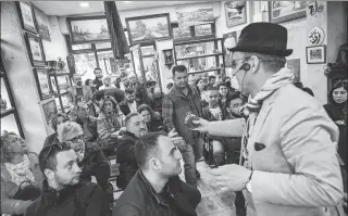  ?? OZAN KOSE / AGENCE FRANCE-PRESSE ?? Auctioneer Ali Tuna (right) shows a clock to the audience at an auction house in Istanbul’s Balat district on Feb 3.