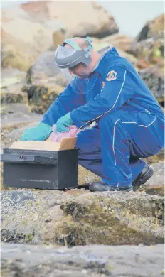  ??  ?? An officer deals with a discarded pyrotechni­c.