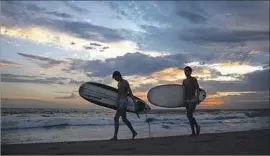  ?? Jay L. Clendenin Los Angeles Times ?? SURFERS Brady Webush, left, and Johnny Byrne of Manhattan Beach end their day in the El Porto area of the city Tuesday.