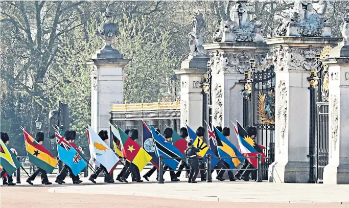  ??  ?? A guard of honour, carrying the flags of all 53 of the Commonweal­th nations, arrives at Buckingham Palace in London, ahead of the formal opening ceremony