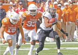  ?? MICHAEL THOMAS/THE ASSOCIATED PRESS ?? Oklahoma State receiver Jalen McCleskey, right, dodges Texas defenders Brandon Jones, left, and Gary Johnson on Saturday in Austin, Texas. Oklahoma State won 13-10 in overtime.