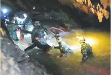  ?? PHOTO BY THAM LUANG RESCUE OPERATION CENTER VIA AP ?? Thai rescue teams use headlamps to enter a pitch-black cave complex where 12 boys and their soccer coach went missing in Mae Sai, Chiang Rai province, northern Thailand, this past week. The group was discovered late Monday after 10 days totally cut off...